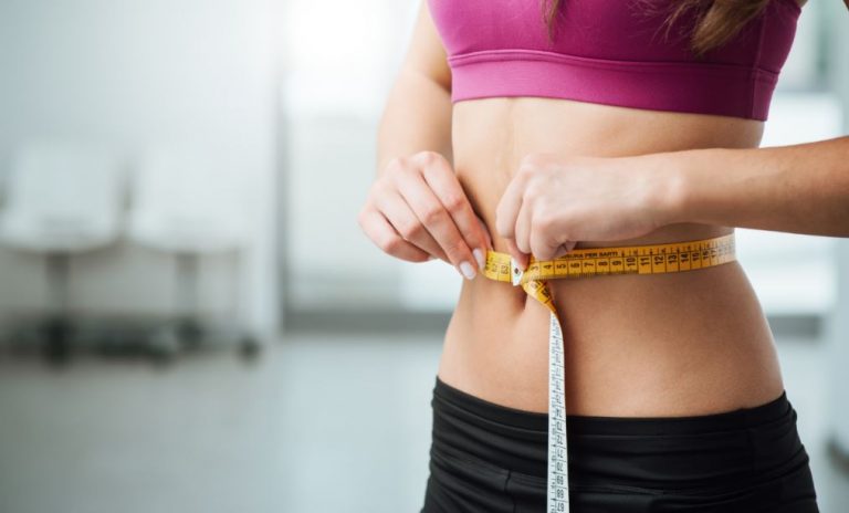 mulher medindo a cintura com uma fita métrica