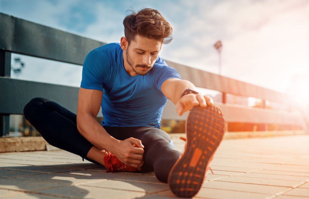 Homem alongando a perna sentado no chão