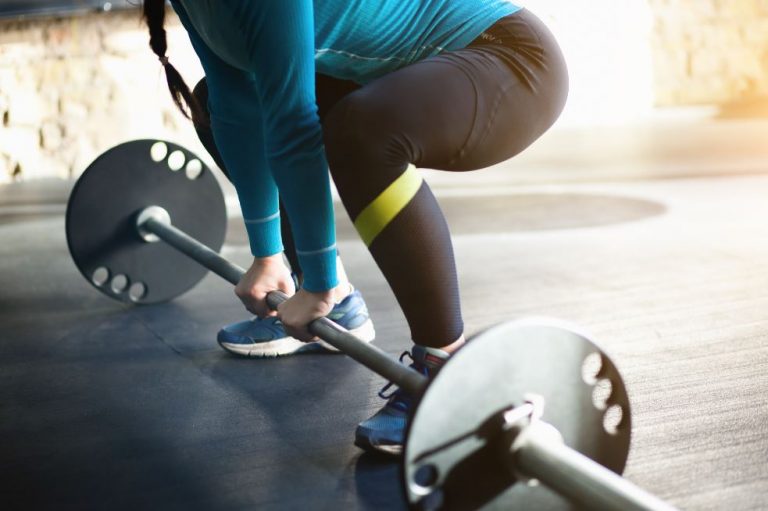 Mulher fazendo o levantamento terra na academia com pesos