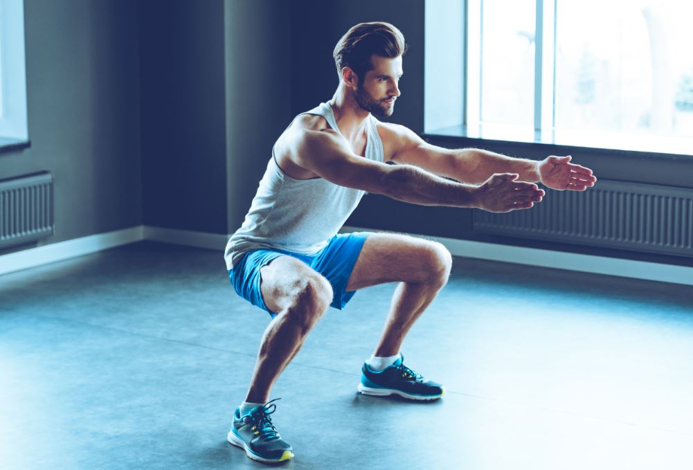 Homem fazendo agachamento na academia