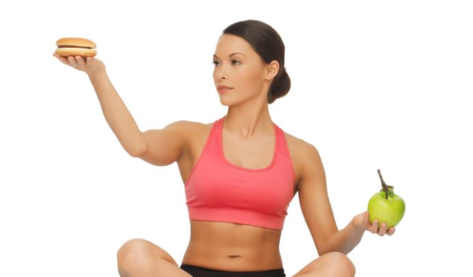 Mulher escolhendo entre um hamburguer e uma maçã