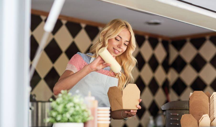 Mulher colocando maionese no seu lanche