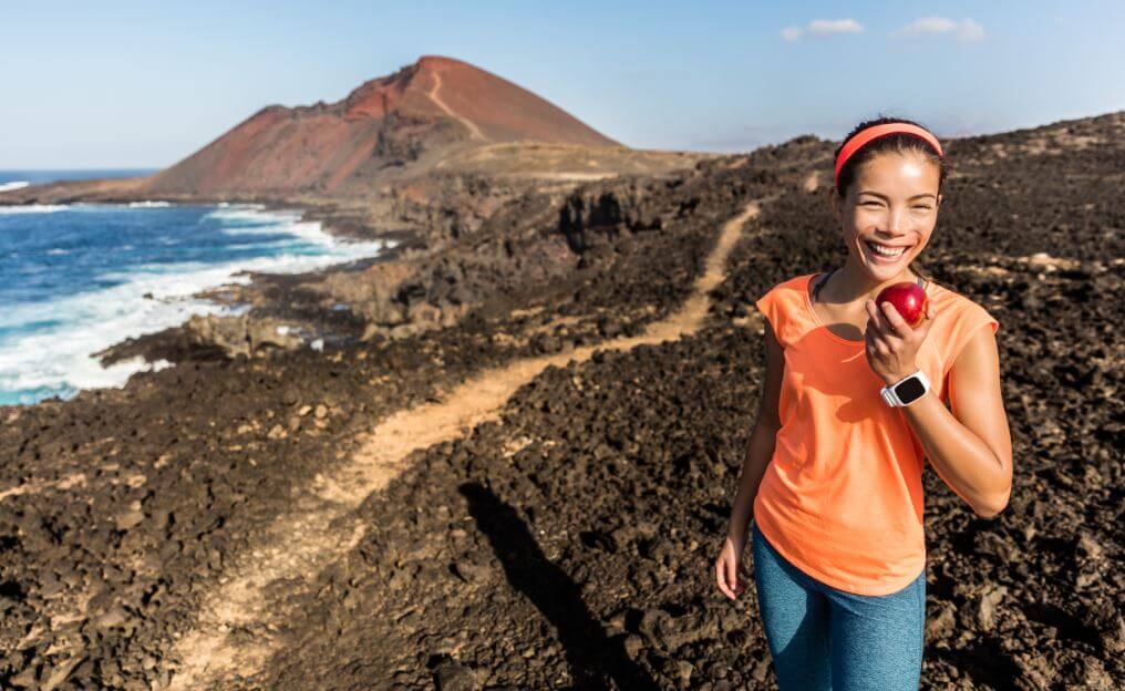 Mulher comendo fruta em trilha