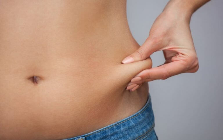 Mulher apertando a gordura da barriga