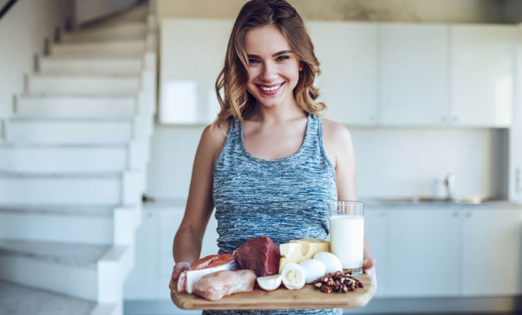 Mulher com uma bandeja de alimentos protéicos