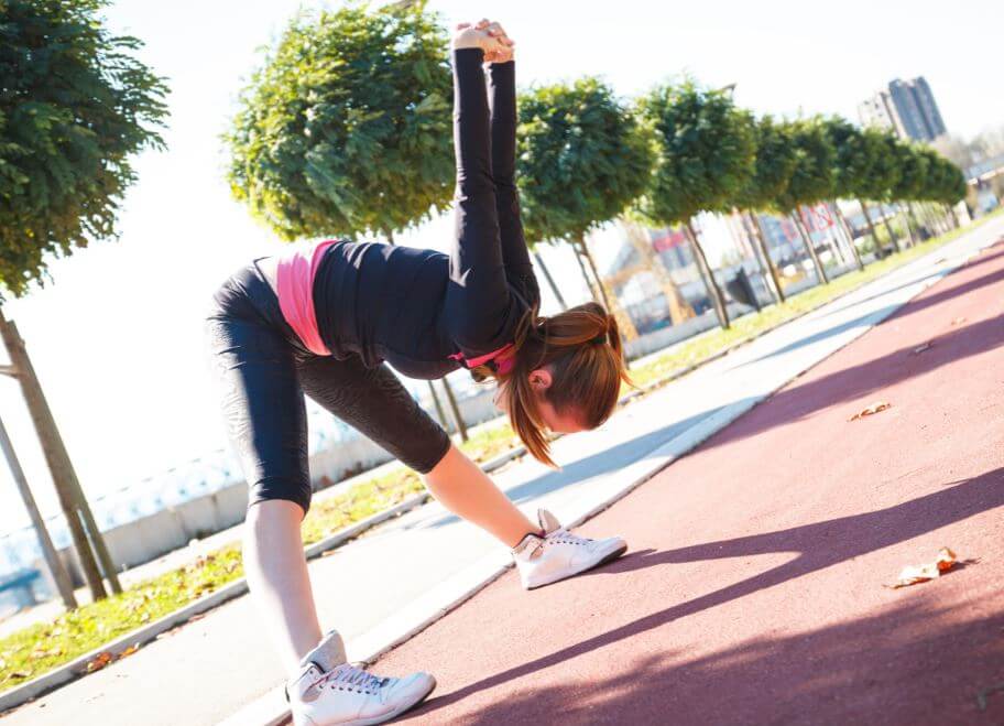 Mulher se alongando em uma pista de corrida