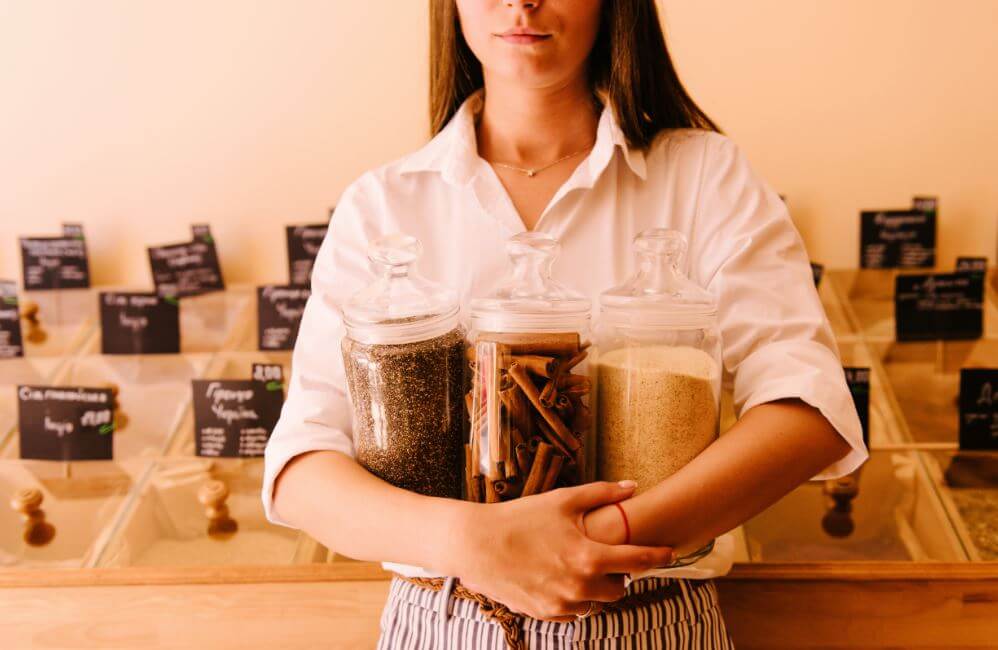 Mulher segurando potes de canela em pó e em pau