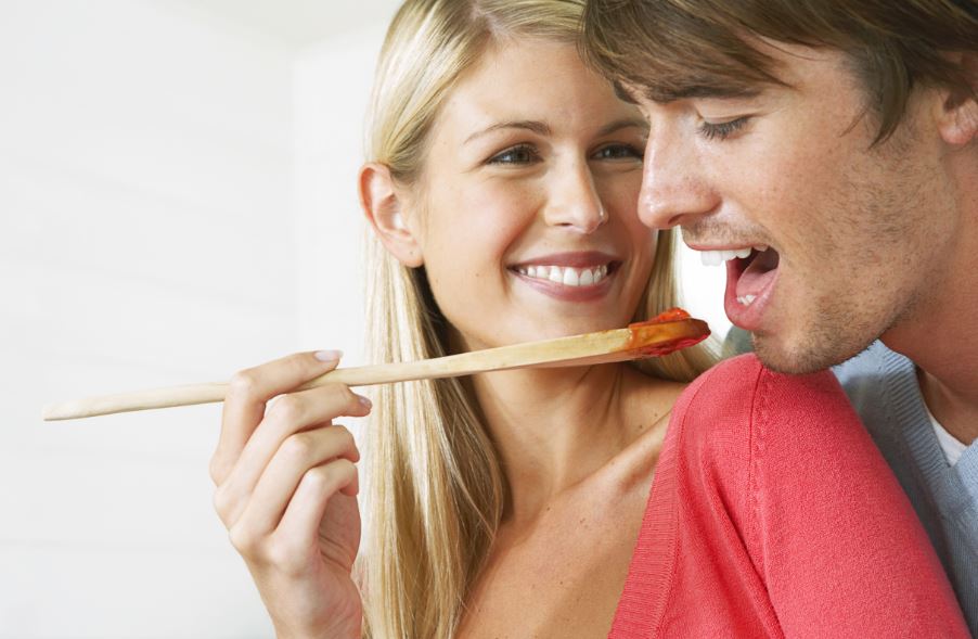 Mulher cozinhando molho de tomate com o marido