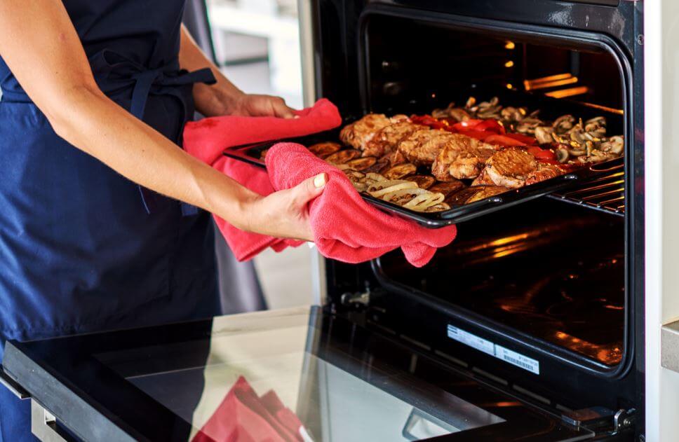 Mulher retirando comida do forno