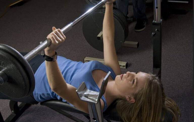 Menina fazendo supino com barra