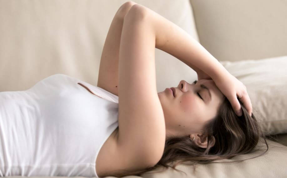 Menina deitada com as mãos na cabeça parecendo preocupada