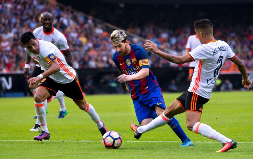 Jogador do Barcelona driblando três jogadores em campo