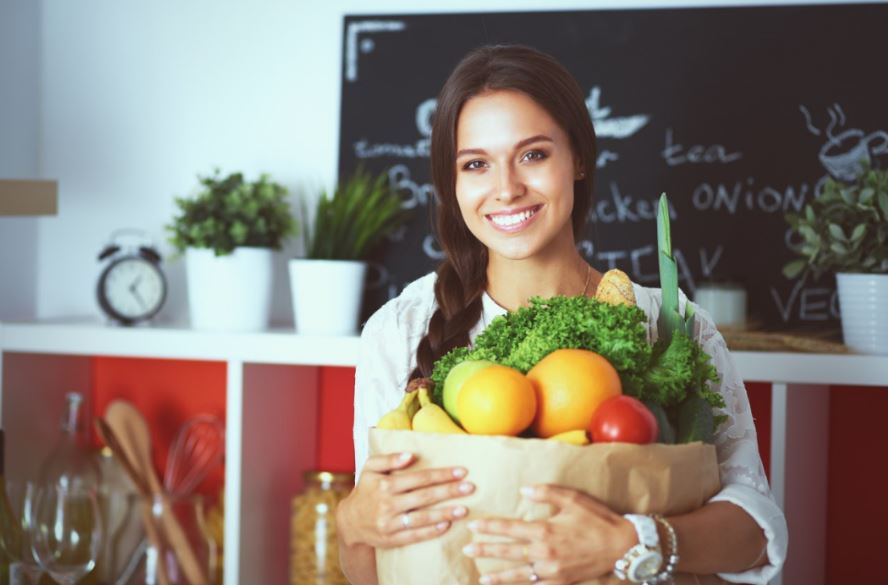 Mulher com uma sacola de compras com verduras, frutas e legumes
