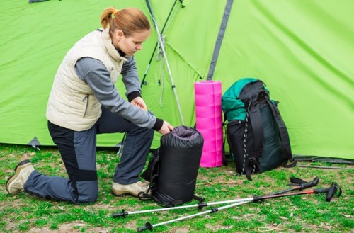Mulher guardando um saco de dormir