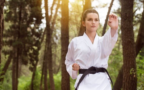 Mulher praticando artes marciais na floresta