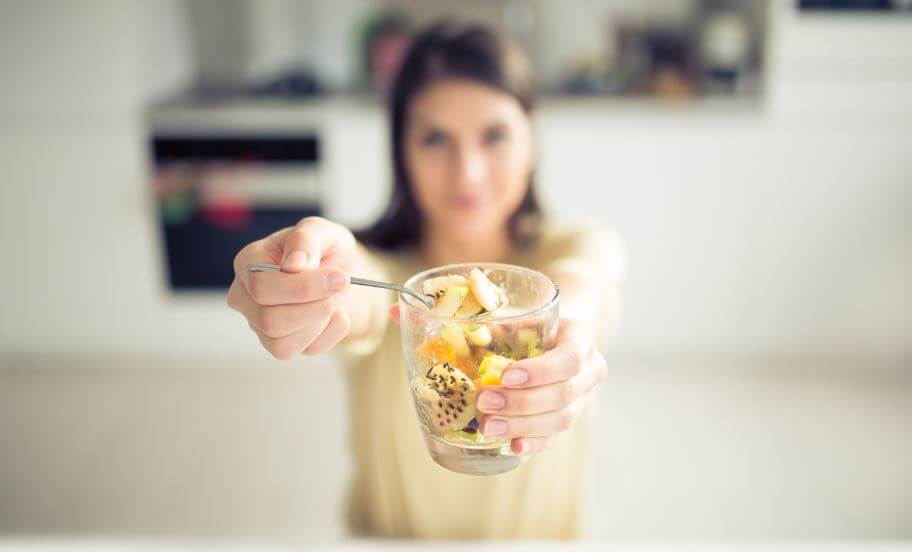 Menina comendo um pote de fruta com sementes