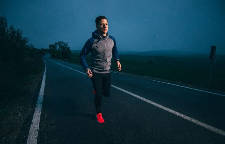 Homem correndo de noite na estrada