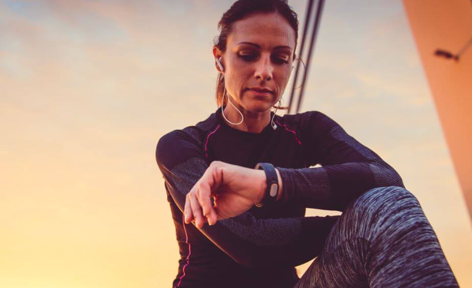 Mulher conferindo relógio ao fazer esporte